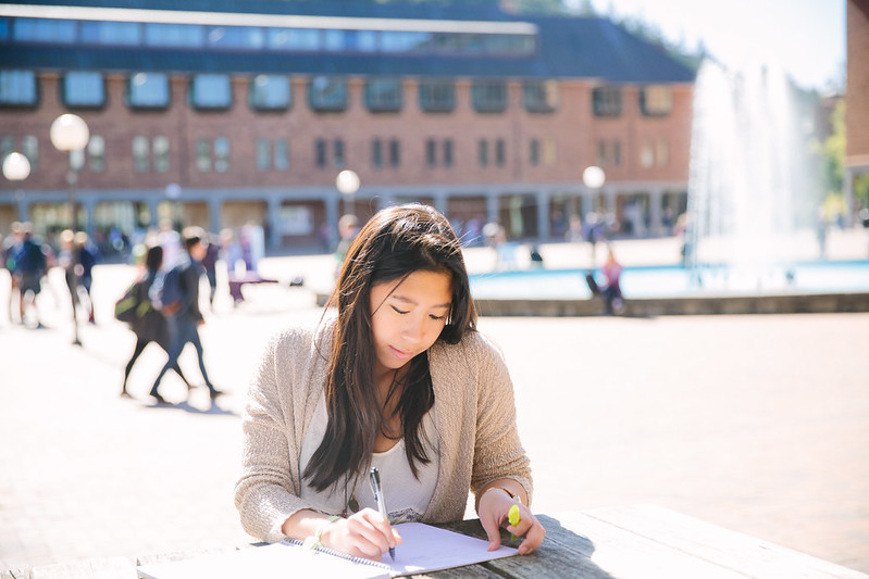 Student with long, dark hair writing in a notebook in Red Square.