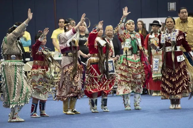 Tribal members dance in regalia 